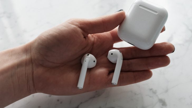 Photo of someone holding airpods and charging case