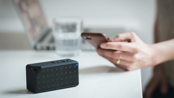 Photo of person holding iphone near a external speaker
