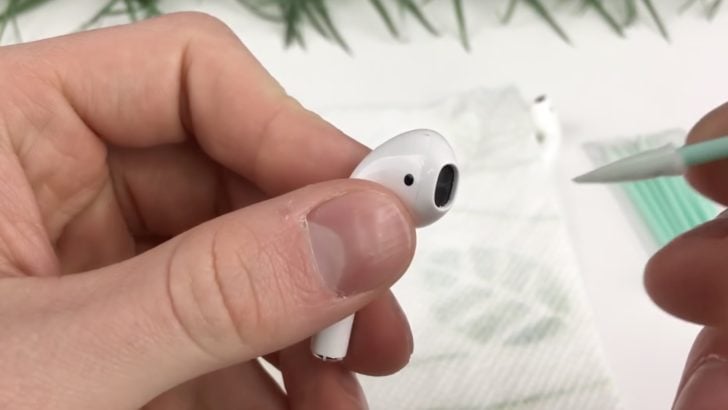 Photo of person cleaning the speaker mesh of airpods