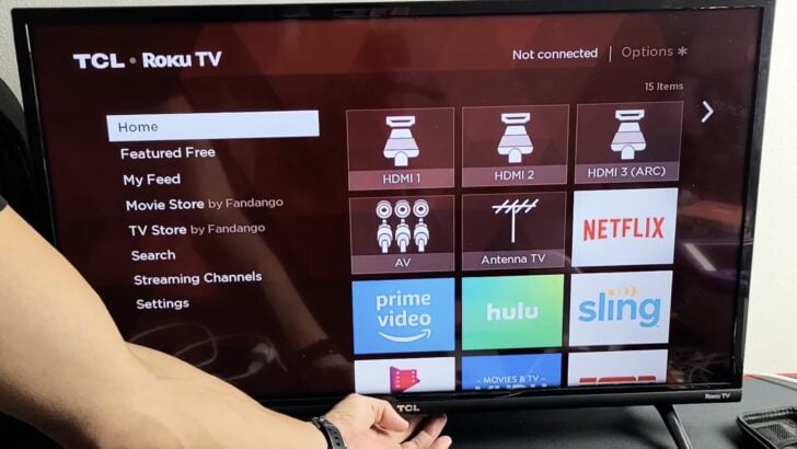 Photo of person checking the tcl roku tv power button underneath the middle part of the bezel