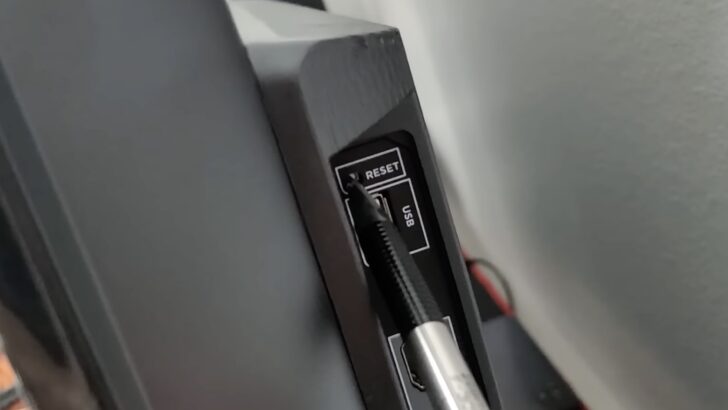 Photo of person pressing reset button on tcl tv using a pen