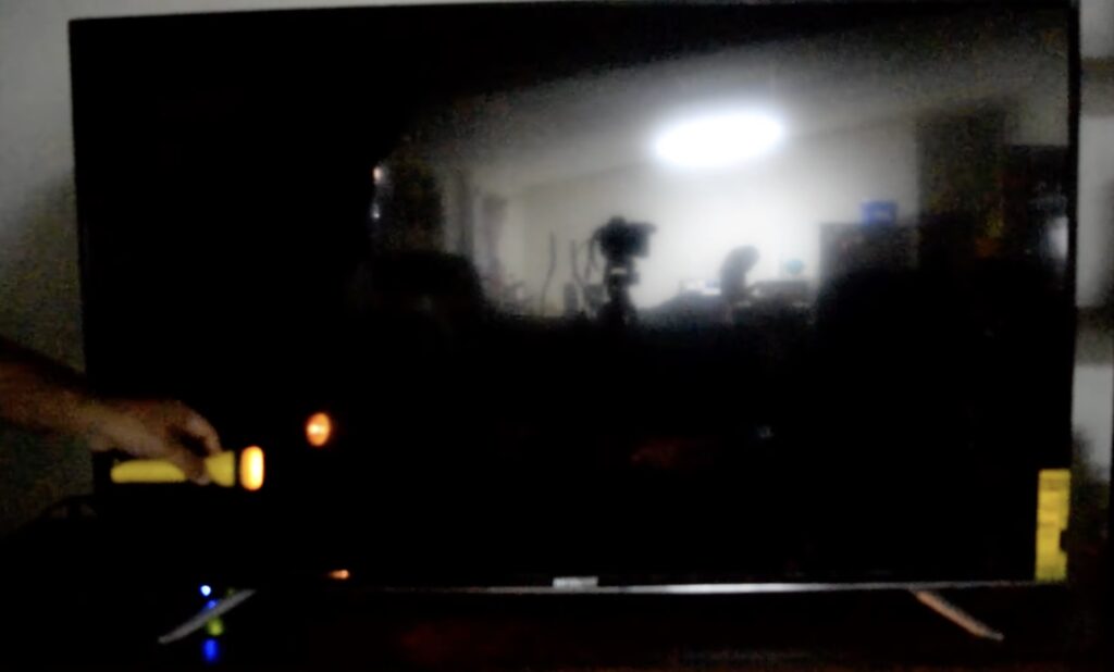 Photo of person using a flashlight to do a broken backlight test on smart tv