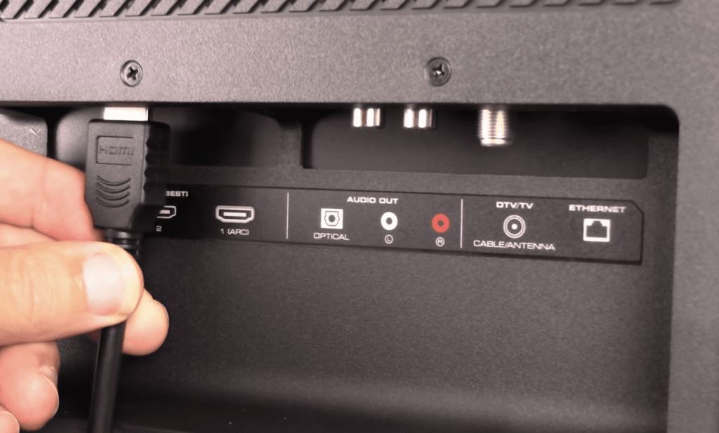 Photo of a person reconnecting the HDMI cable of a cable box on a TV