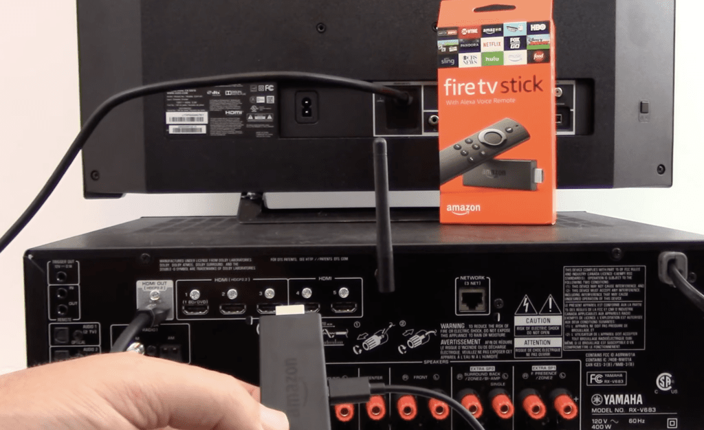 Photo of someone plugging a Firestick into the external speakers connected to a TV