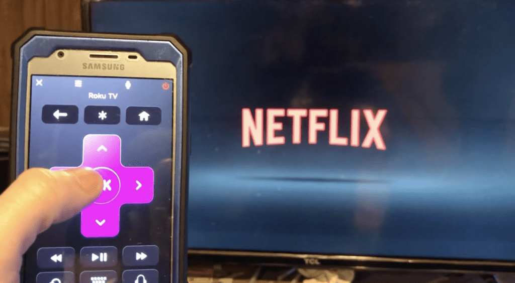 Photo of someone using his smartphone as a TCL Roku TV remove via the Roku app
