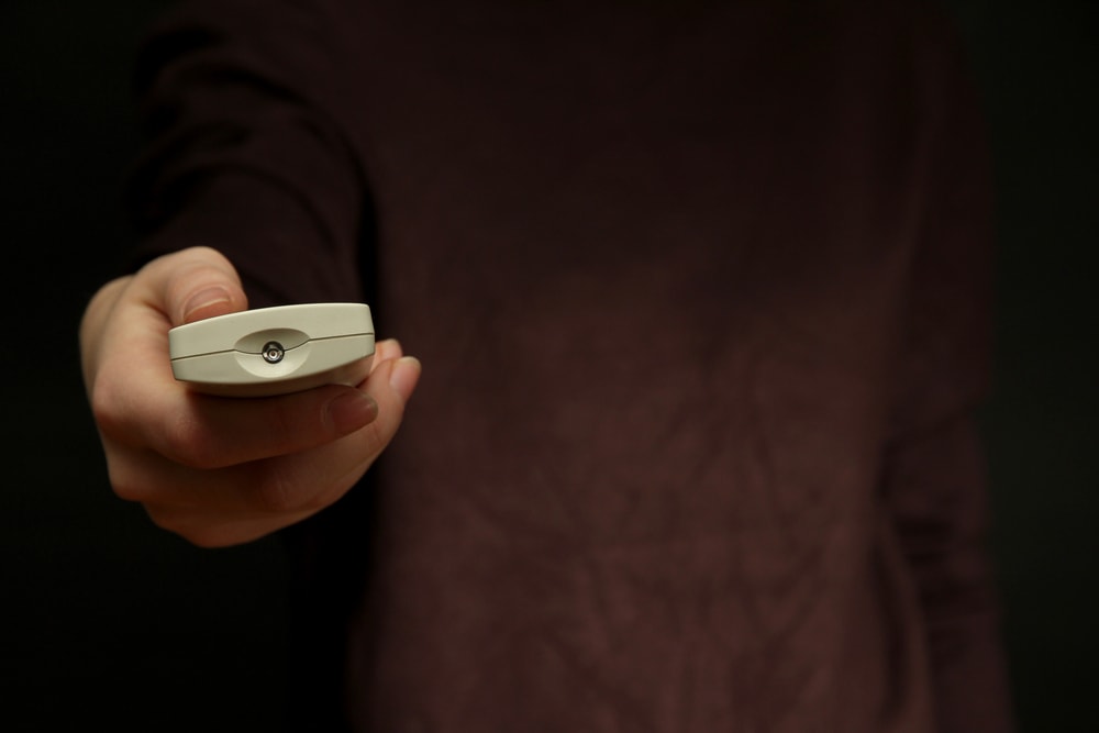 man holding a TV remote control showing it infrared transmitter