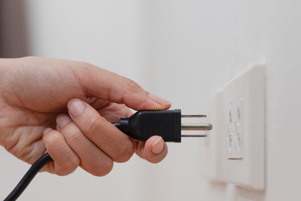 hand plugging out a cord form a power outlet