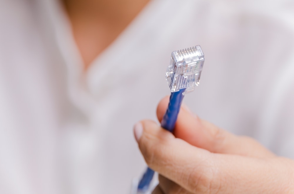 man holding a blue ethernet cable